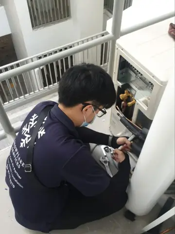 Technician repairing an outdoor unit by the railing