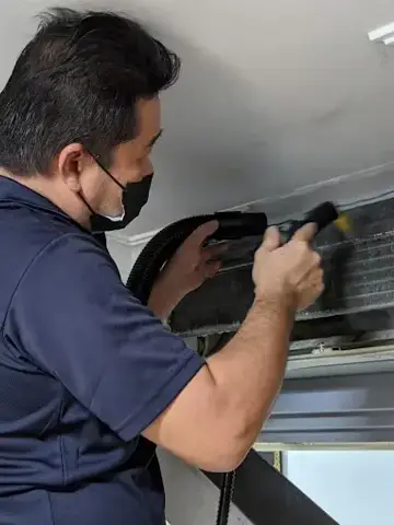 Technician cleaning an indoor unit's coil
