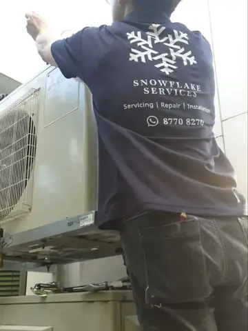 Technician at an outdoor unit, shirt logo showing