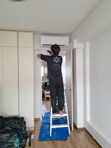 Technician on a step ladder servicing a wall unit